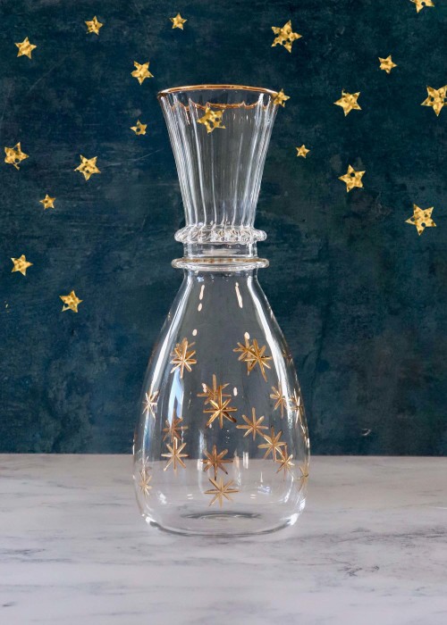 a glass vase with gold stars on a blue background