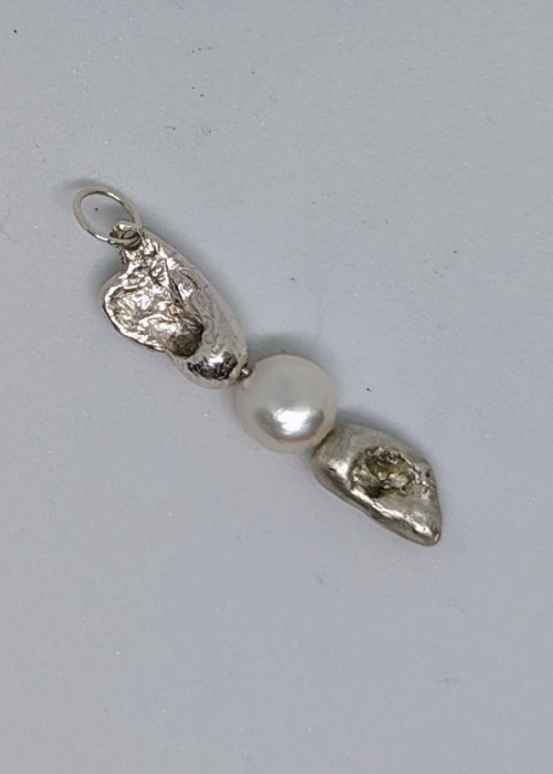 a silver and white pendant with a pearl