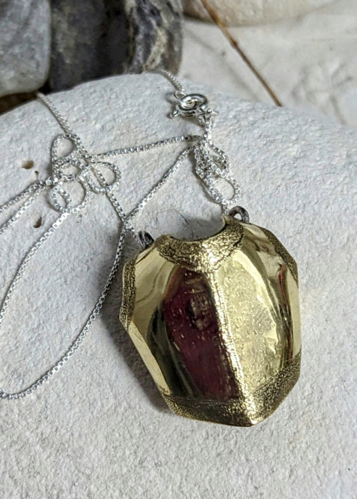 a gold necklace on a white stone