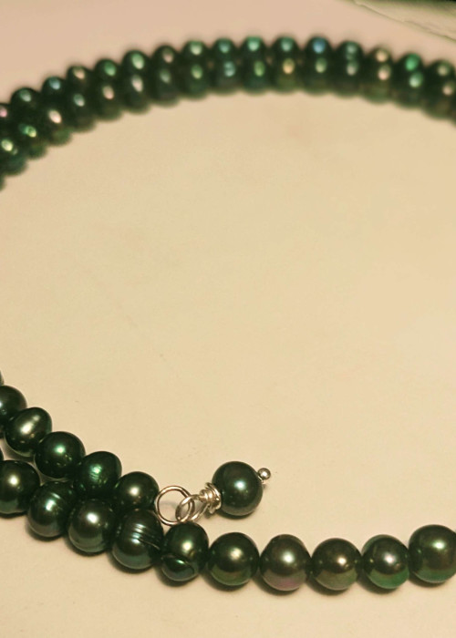 a black pearl necklace on a white surface
