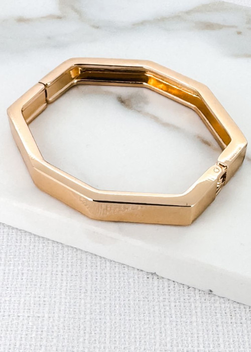 a gold bracelet on a white surface