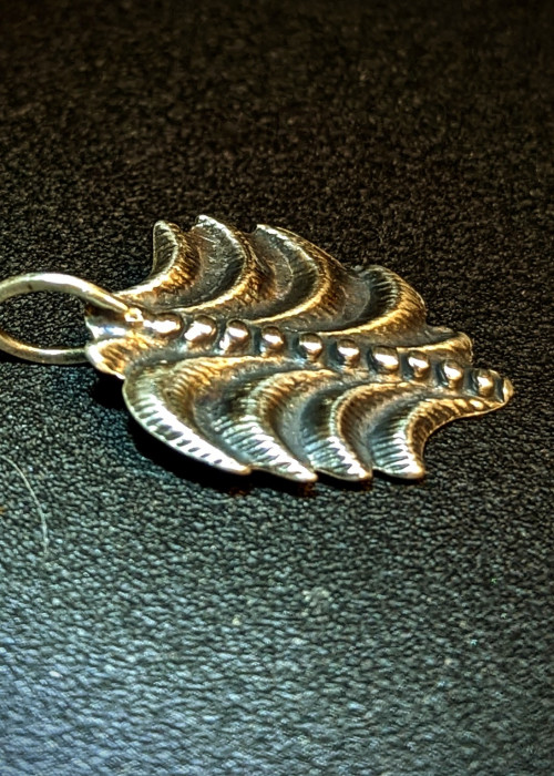 a silver pendant on a black surface