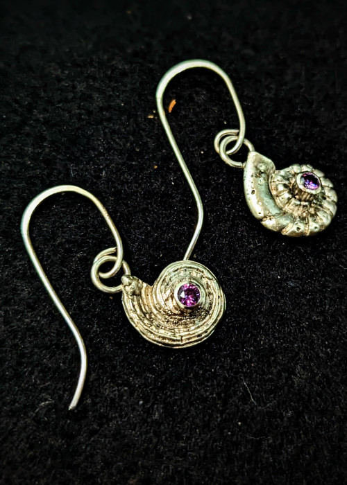 a pair of earrings with a shell and purple gem