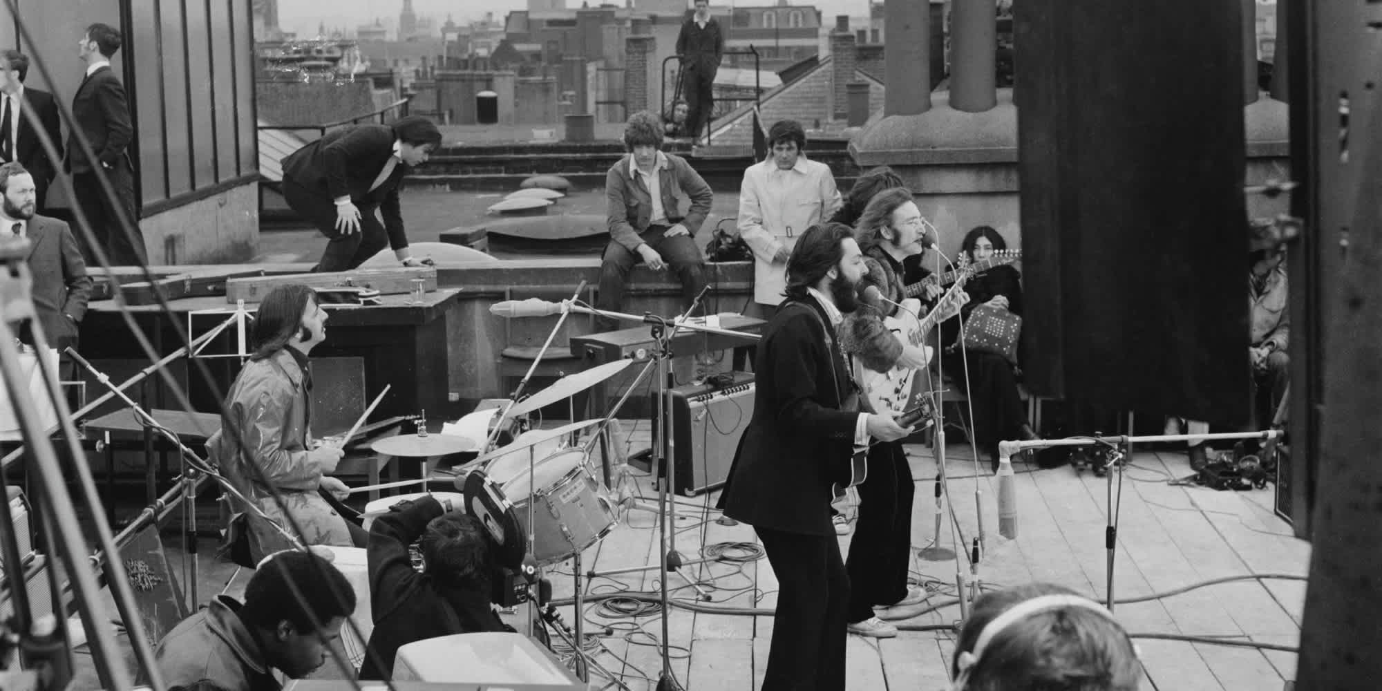 British rock group the Beatles performing their last live public concert on the rooftop of the Apple Organization building for director Michael Lindsey-Hogg's film documentary, 'Let It Be,' on Savile Row, London, UK, 30th January 1969; drummer Ringo Starr sits behind his kit, singer-songwriters Paul McCartney and John Lennon (1940 - 1980) perform at their microphones, and guitarist George Harrison (1943 - 2001) stands behind them. Lennon's wife Yoko Ono sits at right. (Photo by Evening Standard/Hulton Archive/Getty Images)