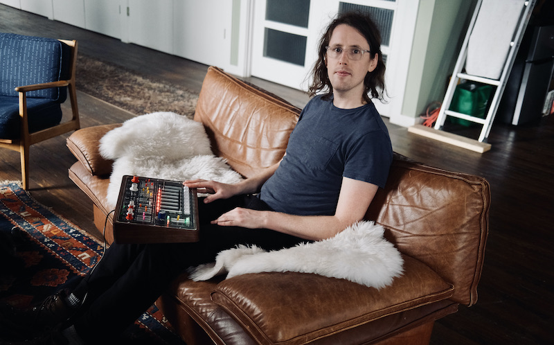 Matthew O'Connell sitting on a couch with the Balsam synth on his lap