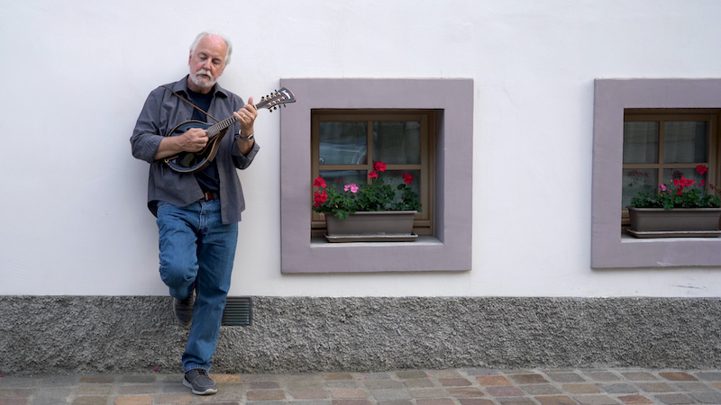 john posing against a building wall with a mandolin