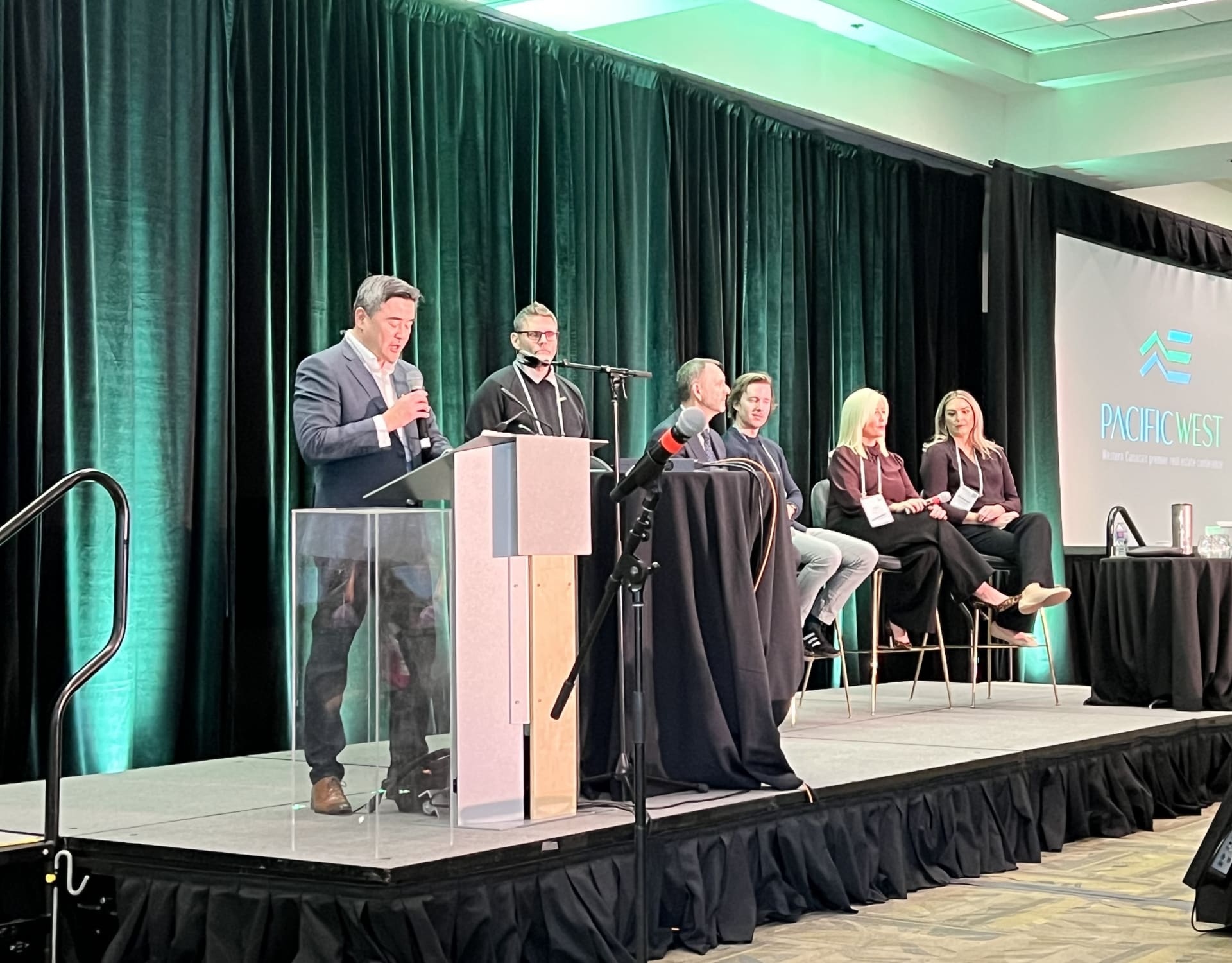 Lawrence Liu, REW's VP of Sales, introducing the speakers of a panel at PacificWest 2025.