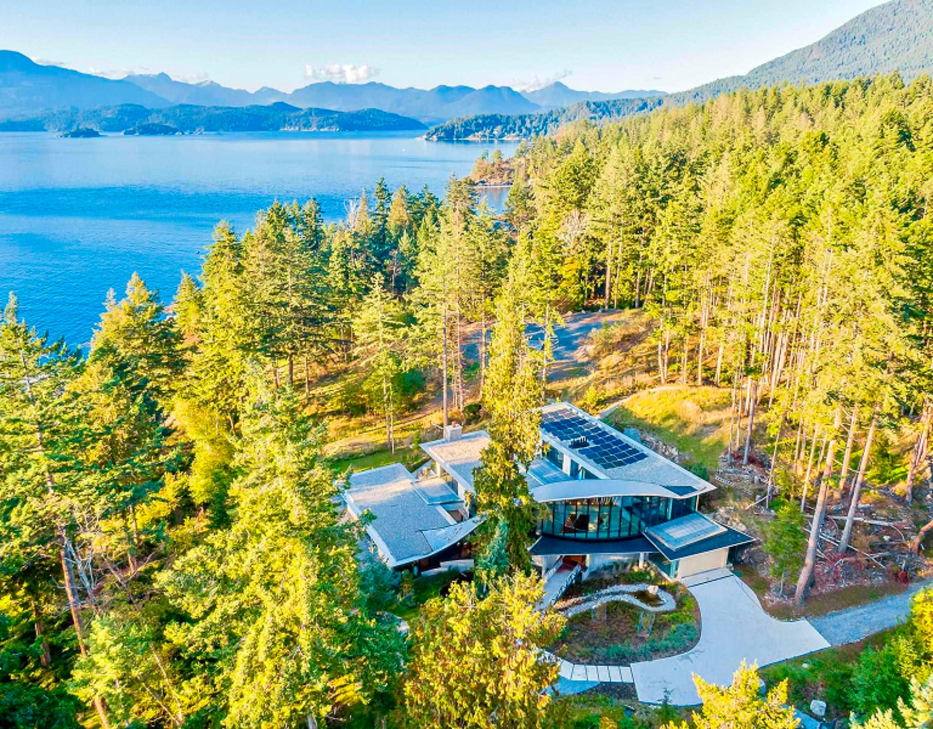 A home with solar panels overlooking a serene blue bay.