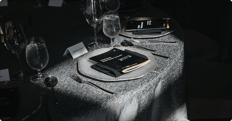A place setting at the REW Real Estate Awards featuring a printed program.