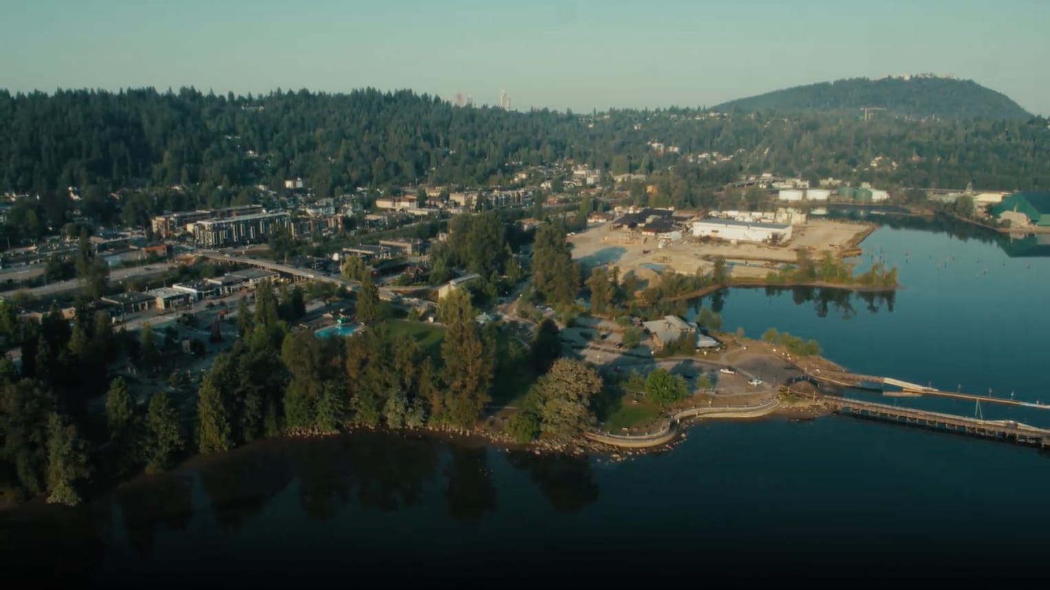 An aerial view of Port Moody reveals a diverse landscape of homes, tree-lined streets, and parks, all set against a backdrop of urban and natural beauty.
