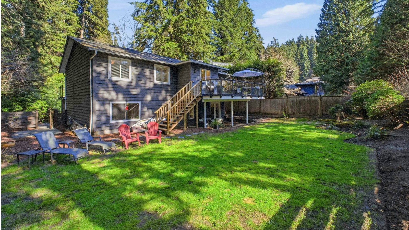 A cozy wooden cabin nestled in a lush, forested landscape, with a well-maintained lawn and patio area in the foreground, inviting visitors to relax and enjoy the serene outdoor setting.