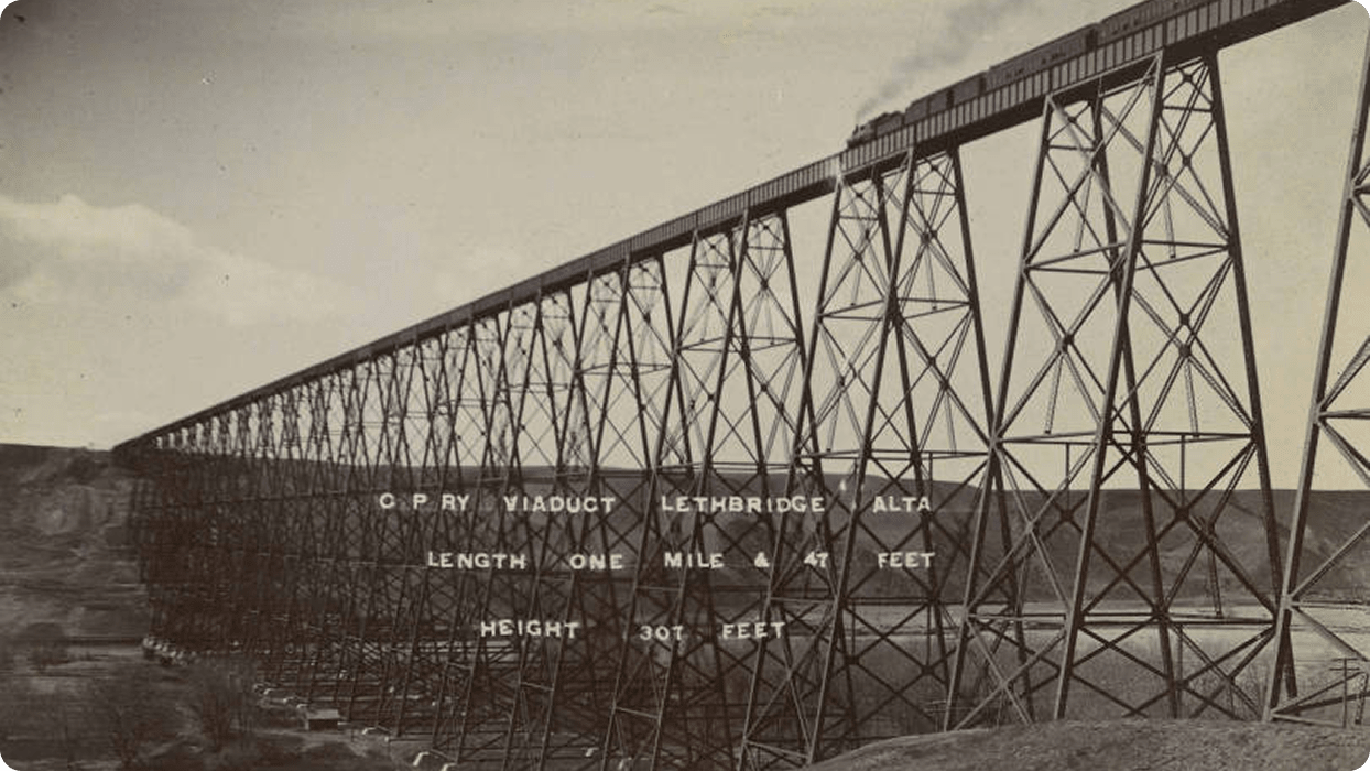 A black and white photograph of the Lethbridge Viaduct (commonly known as the High Level Bridge) over the Oldman River. It was completed in June 1909.