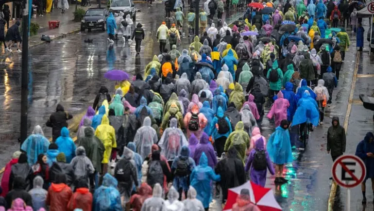 Peregrinos con paraguas y pilotos caminan hacia la Basílica de Luján bajo la lluvia