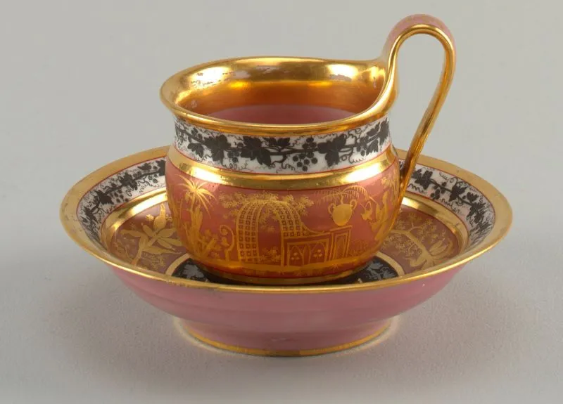 &nbsp; Curved cup with cavetto neck and high loop handle. Overglaze decoration on cup: at bottom, silver vine on black band; center: pink with gold chinoiserie; top: black vine on white. Inside pink, with wide gold band. Saucer with similar decoration, but wreath instead of chinoiserie. c. 1805. Image by&nbsp;Smithsonian Design Museum&nbsp;➚&nbsp;available under a&nbsp;Creative Commons License&nbsp;➚Small cups and high saucers were the norm in early days of tea drinking&nbsp;&nbsp;