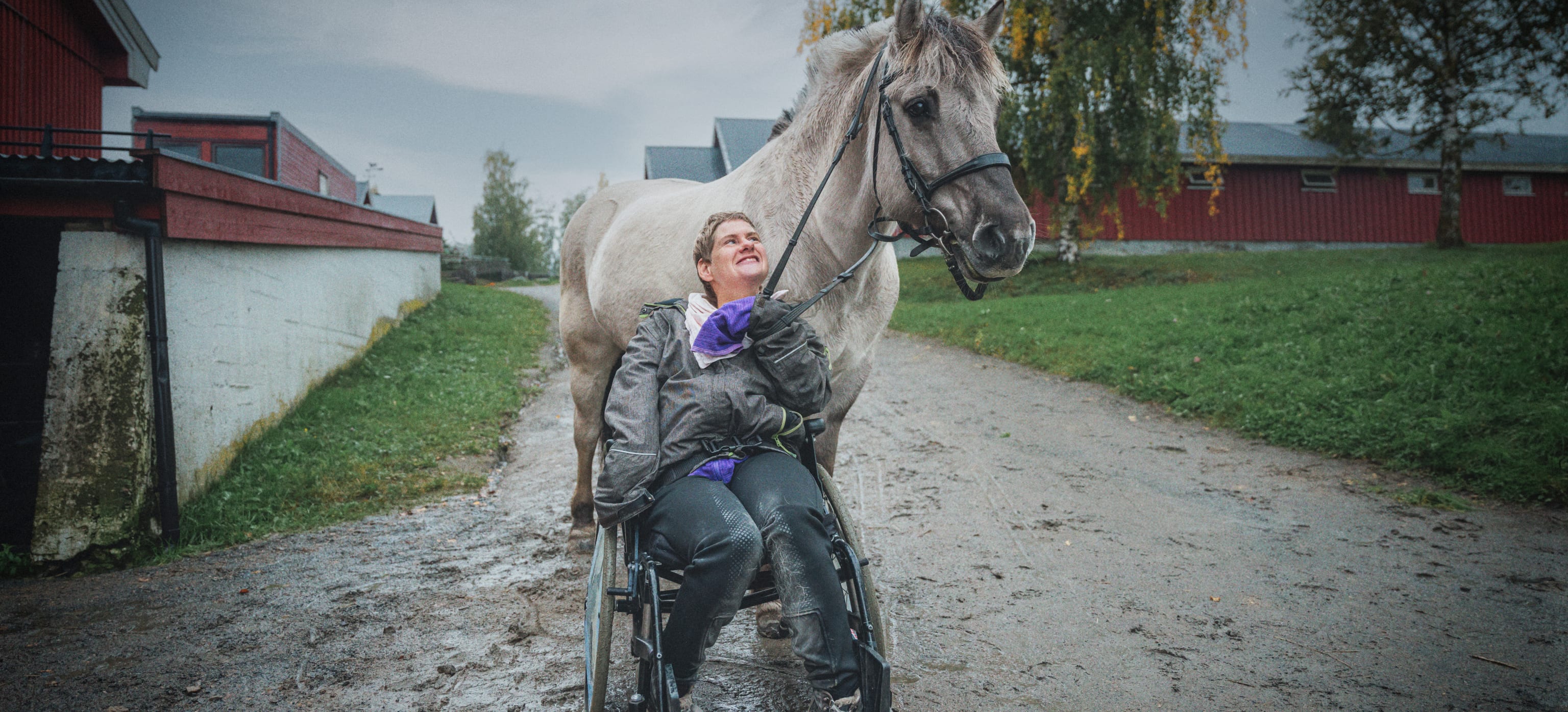 Dame sitter i rullestol og holder en hest.