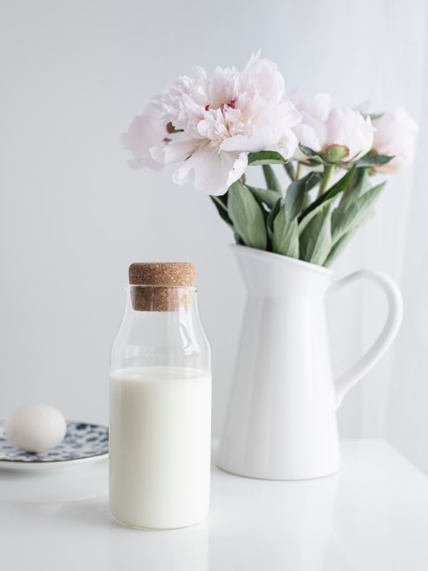 Glass Bottle Of Milk and Vase of Pink Flowers