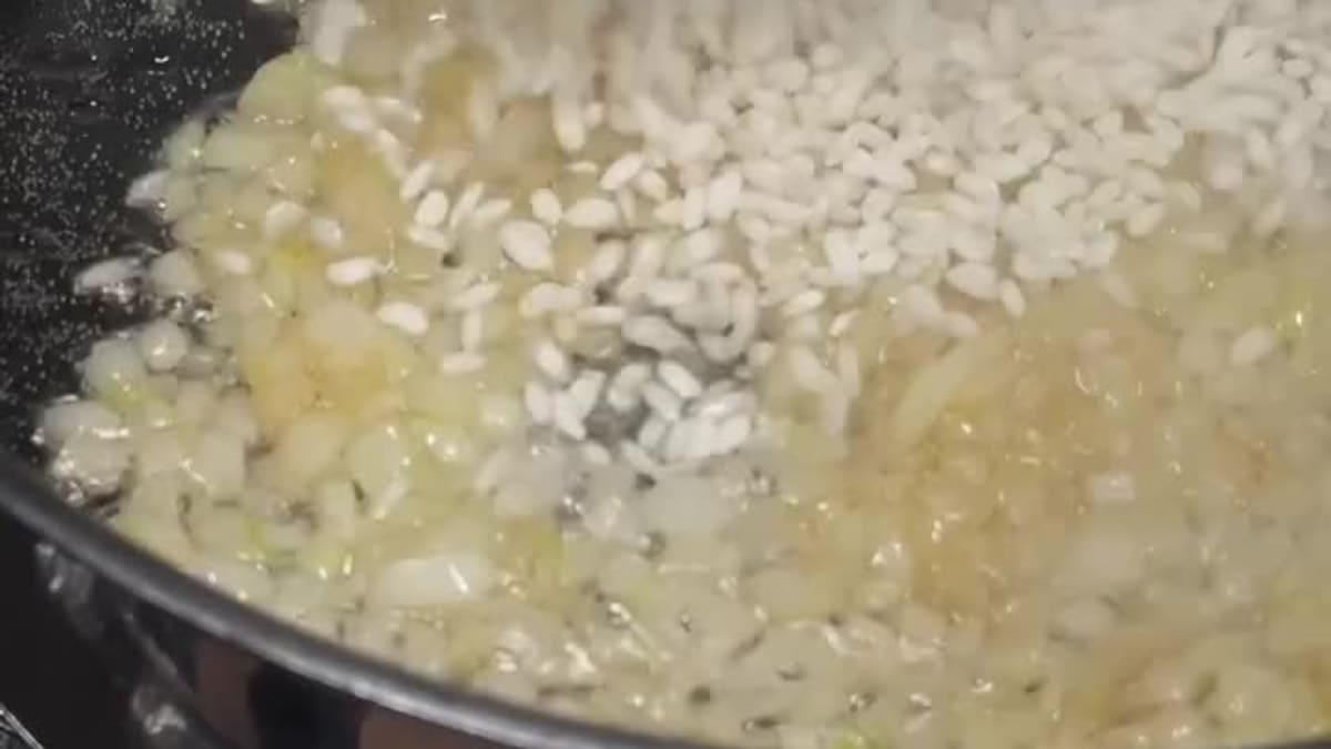 Tarty ser sypany do sosu na patelni podczas przygotowania wytrawnego sernika z makaronu