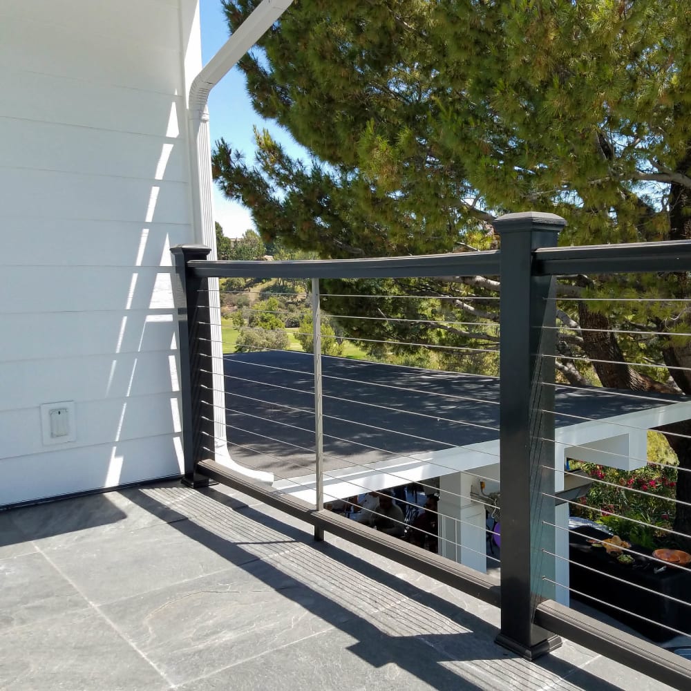 Tensioned cable railing infill between metal posts