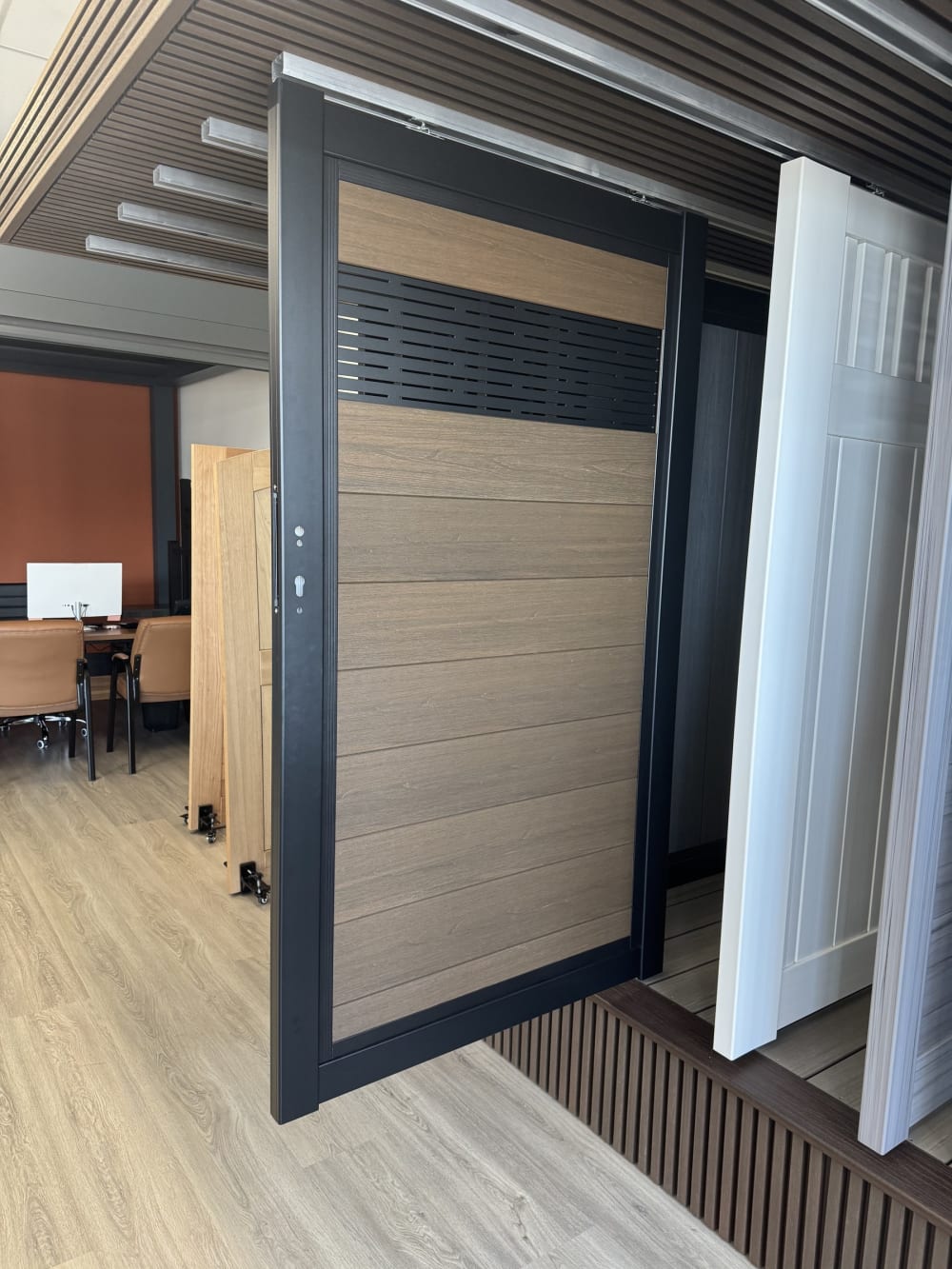 Wood-tone composite gate panel with louvered top in a black aluminum frame