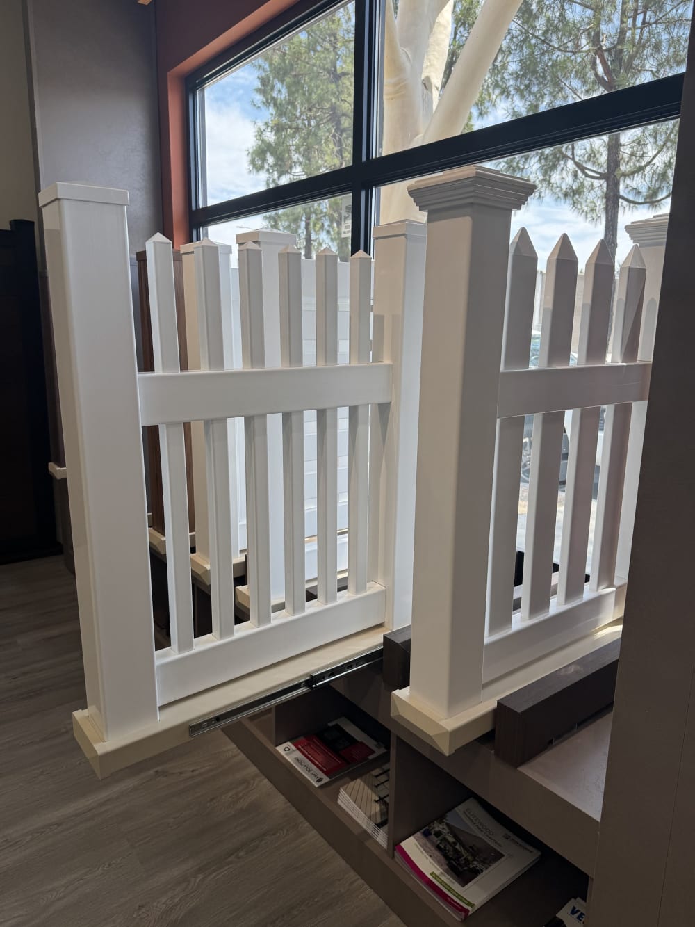 White vinyl picket fence and post cap display beside the showroom window