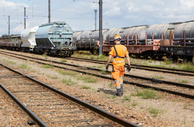 Employé au milieu des rails avec des trains dans le fond