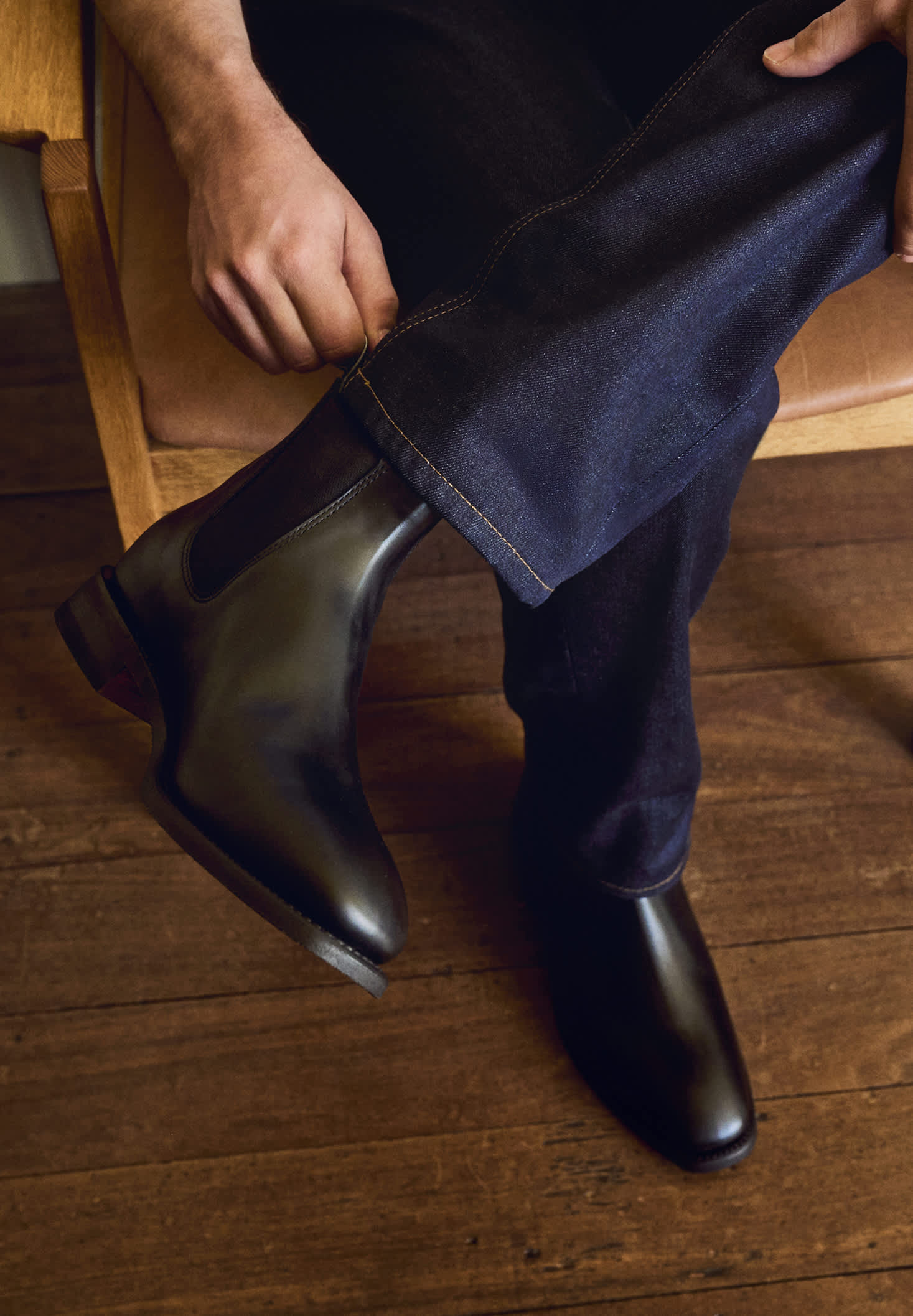 Person wearing brown Chelsea boots and white pants on a plain background