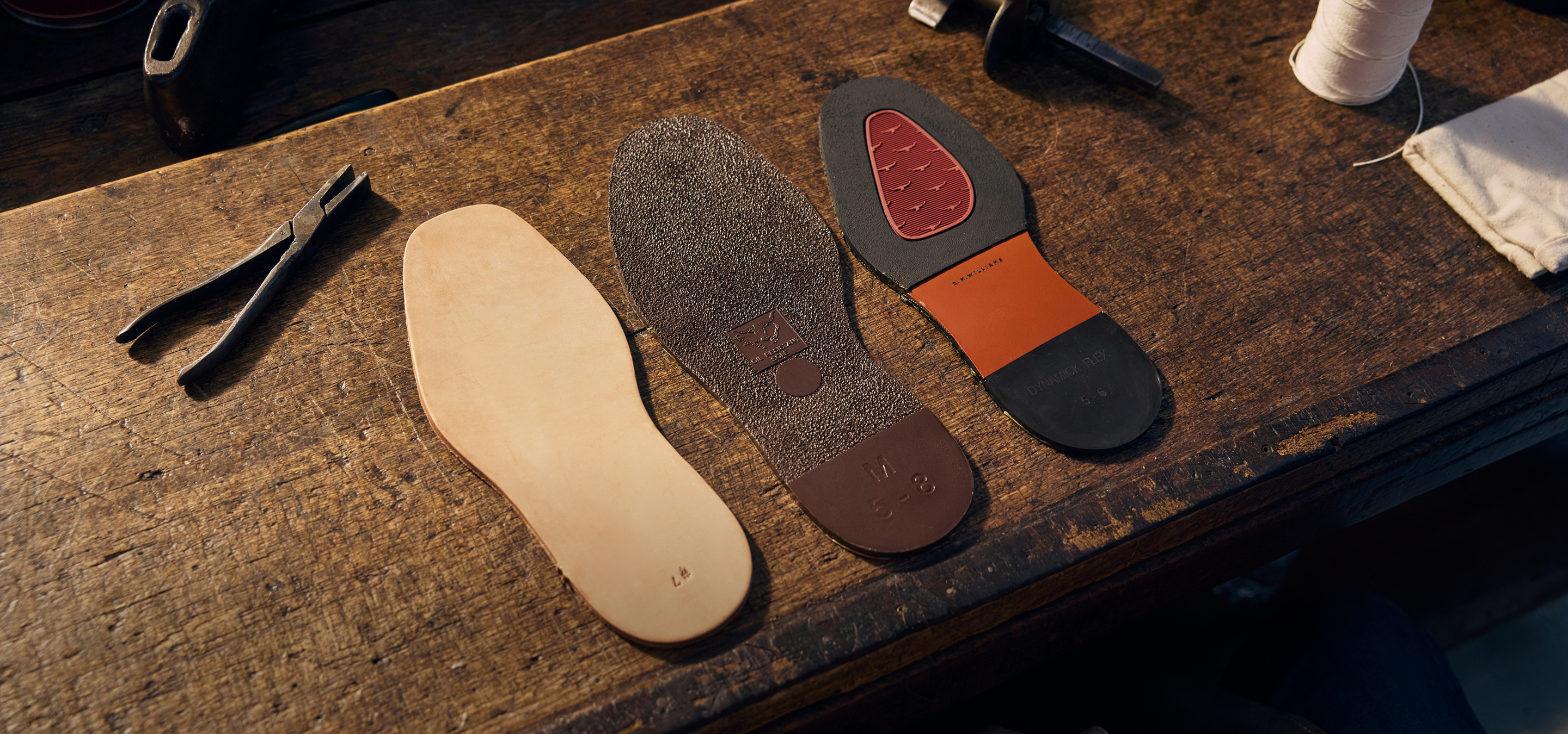 Craftsman holding a shoe sole in a workshop filled with tools