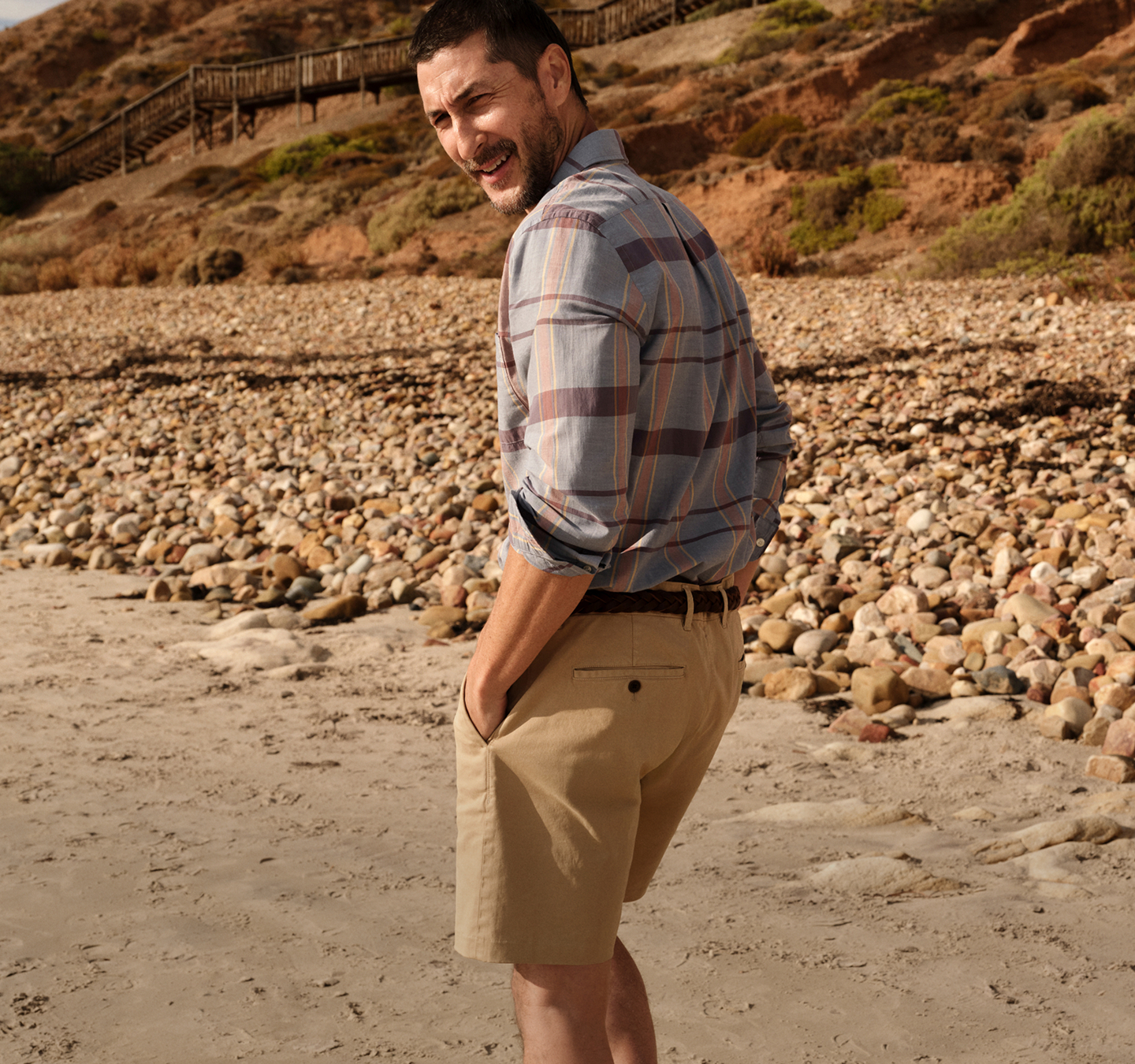 Close-up of a person’s feet in brown Chelsea boots, standing on a wooden surface with a grassy field in the background