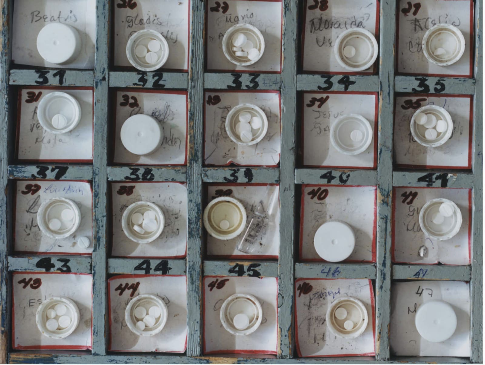 Photograph from above of numbered and named pots with medicine pills inside.