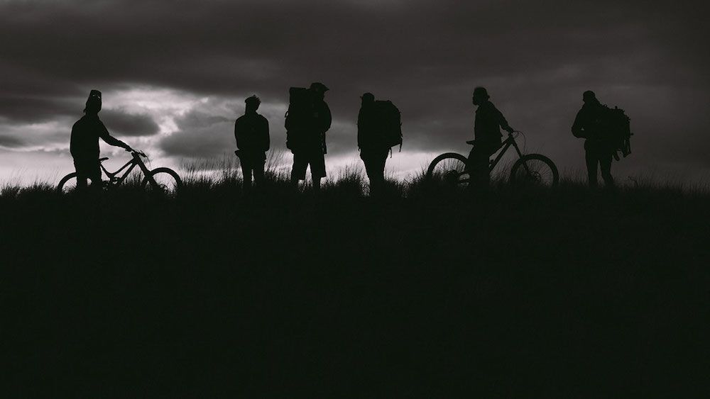 Silhouette of riders with bikes and sunset in background