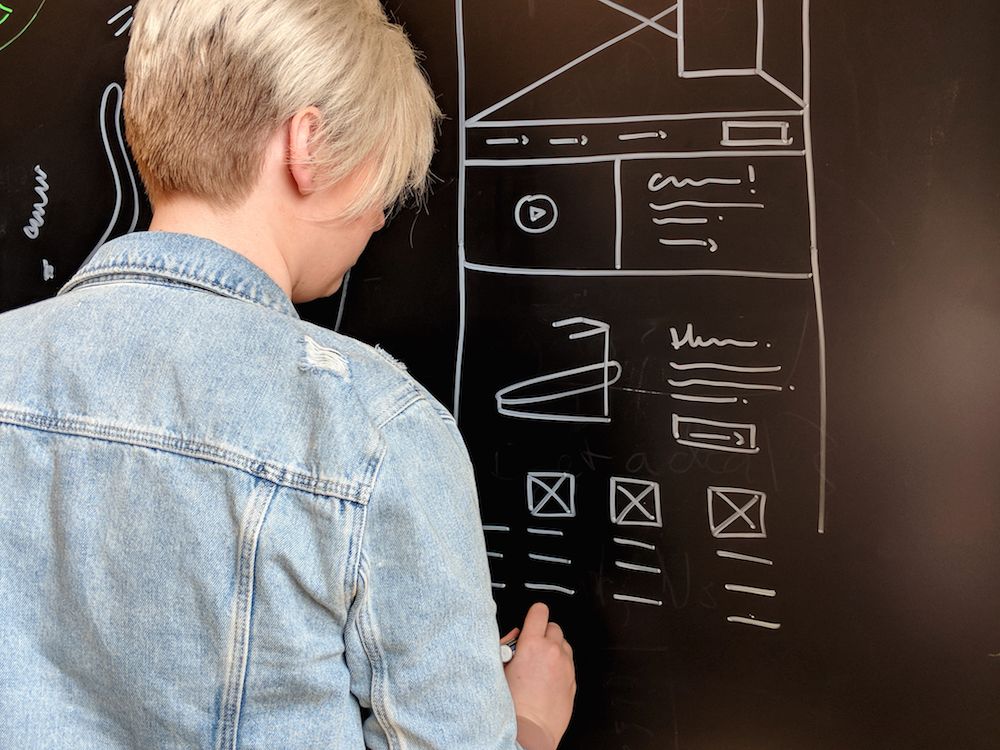 Lacie Webb drawing wireframes on a chalkboard