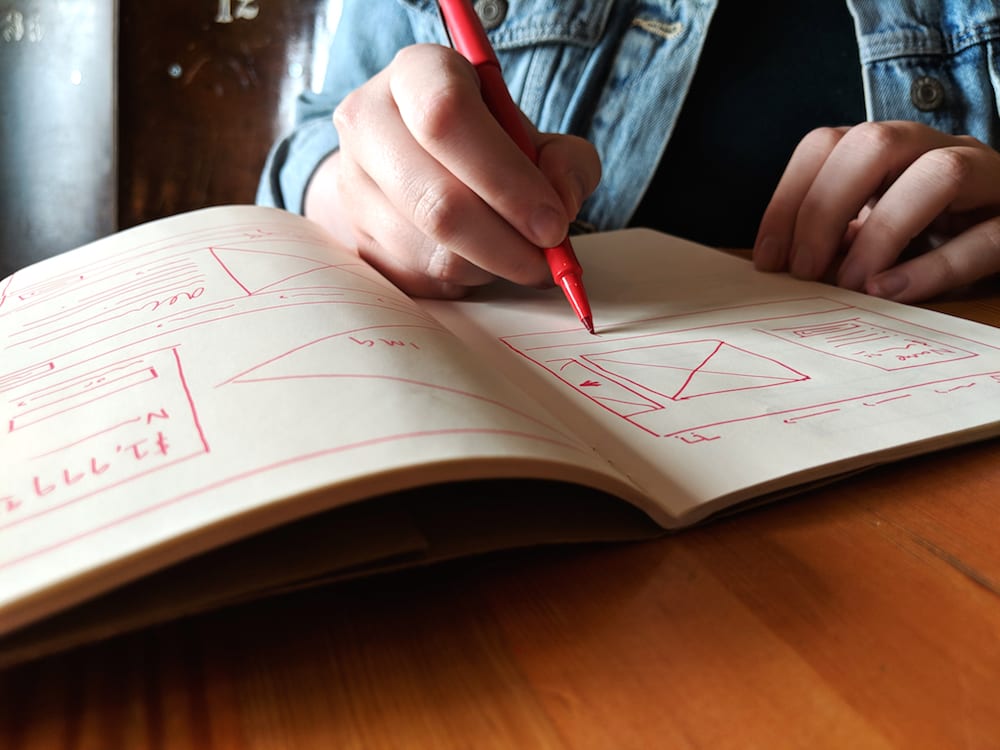 Lacie Webb draws wireframes in a notebook