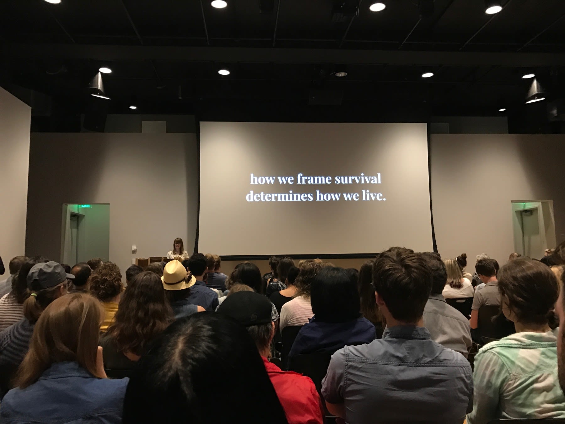 Traci Sym speaking in front of an audience at Creative Mornings PDX - How we frame survival determines how we live