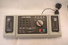 A seventies style pong console, with vertical slider inputs 'docked' to the left and right of the center control console, which has the game configuration buttons and dials.