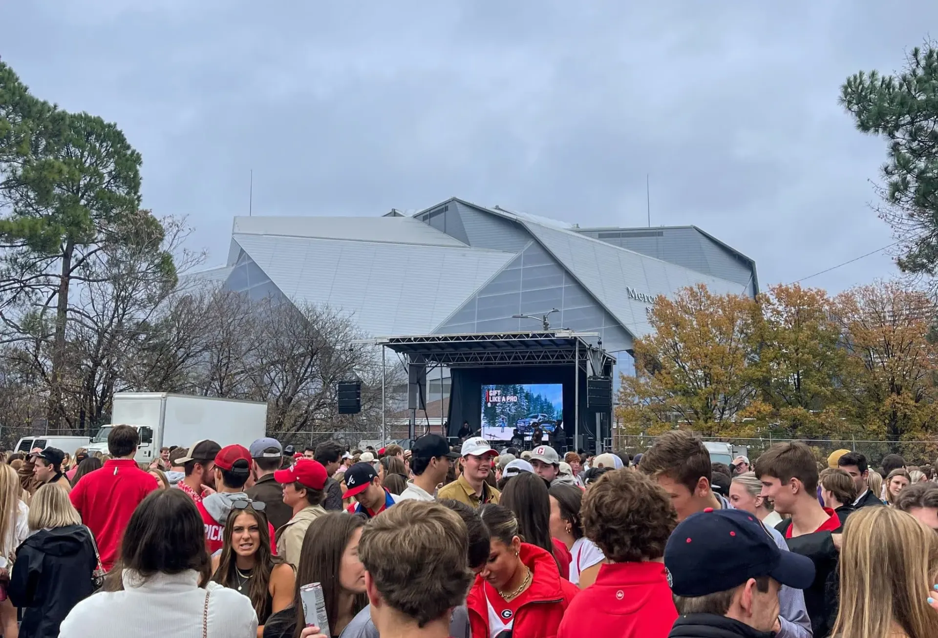 SEC Championship tailgate crowd with mobile stage and LED wall outside Mercedes-Benz Stadium