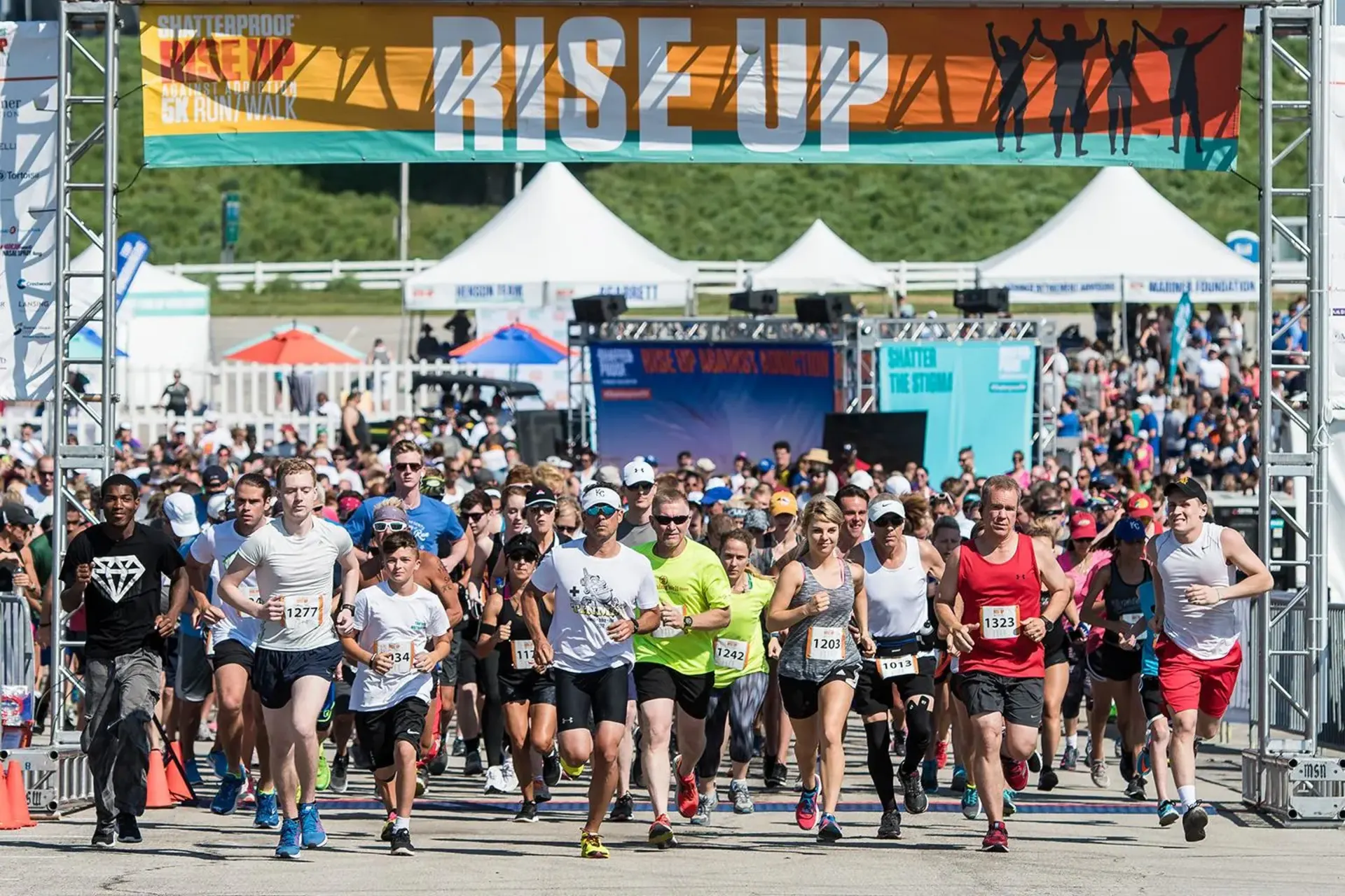 Runners crossing through branded arch at Shatterproof 5K event