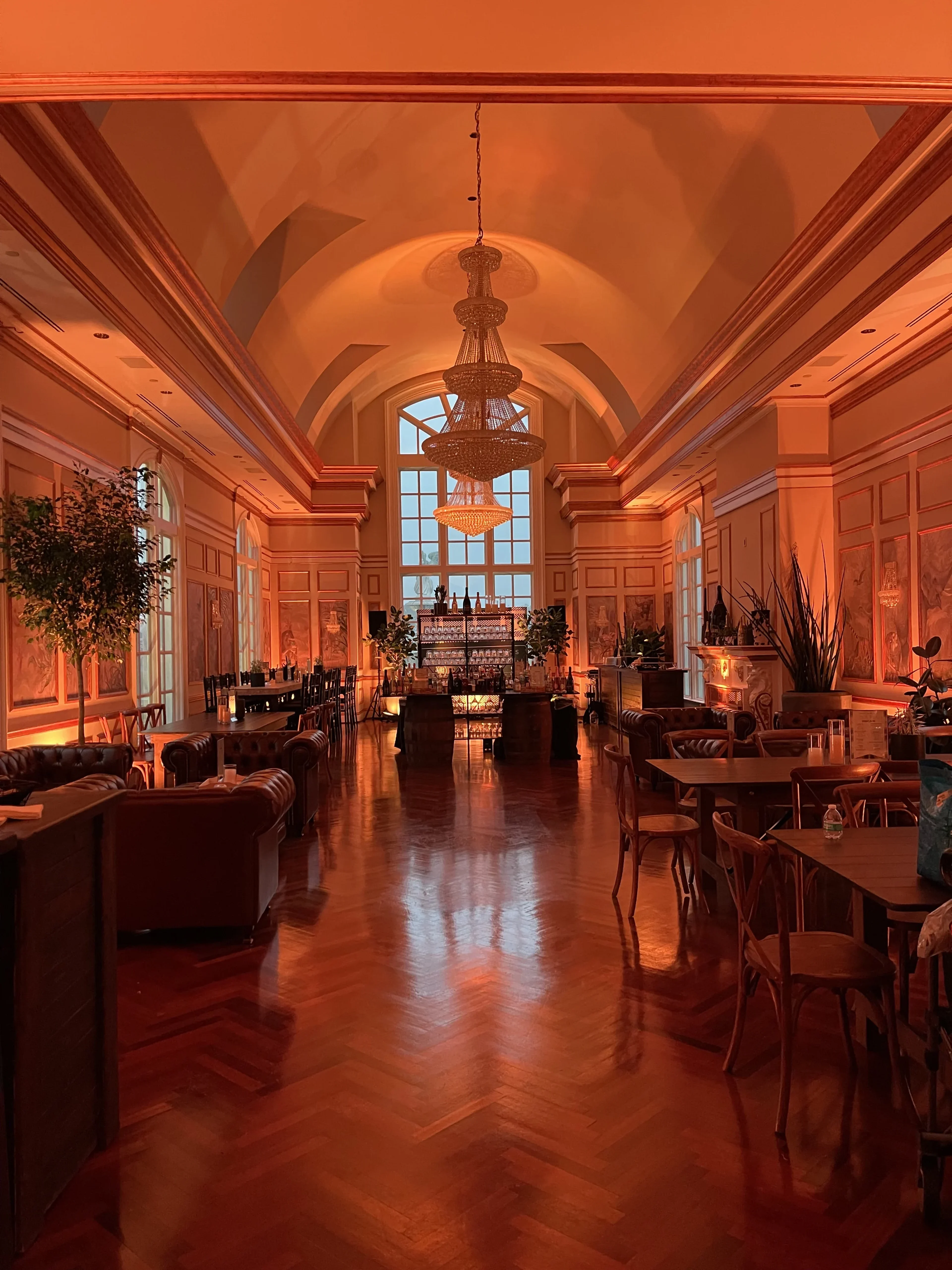 Corporate reception in a vaulted-ceiling atrium lit in warm amber wash with lounge seating and a buffet/bar in the background