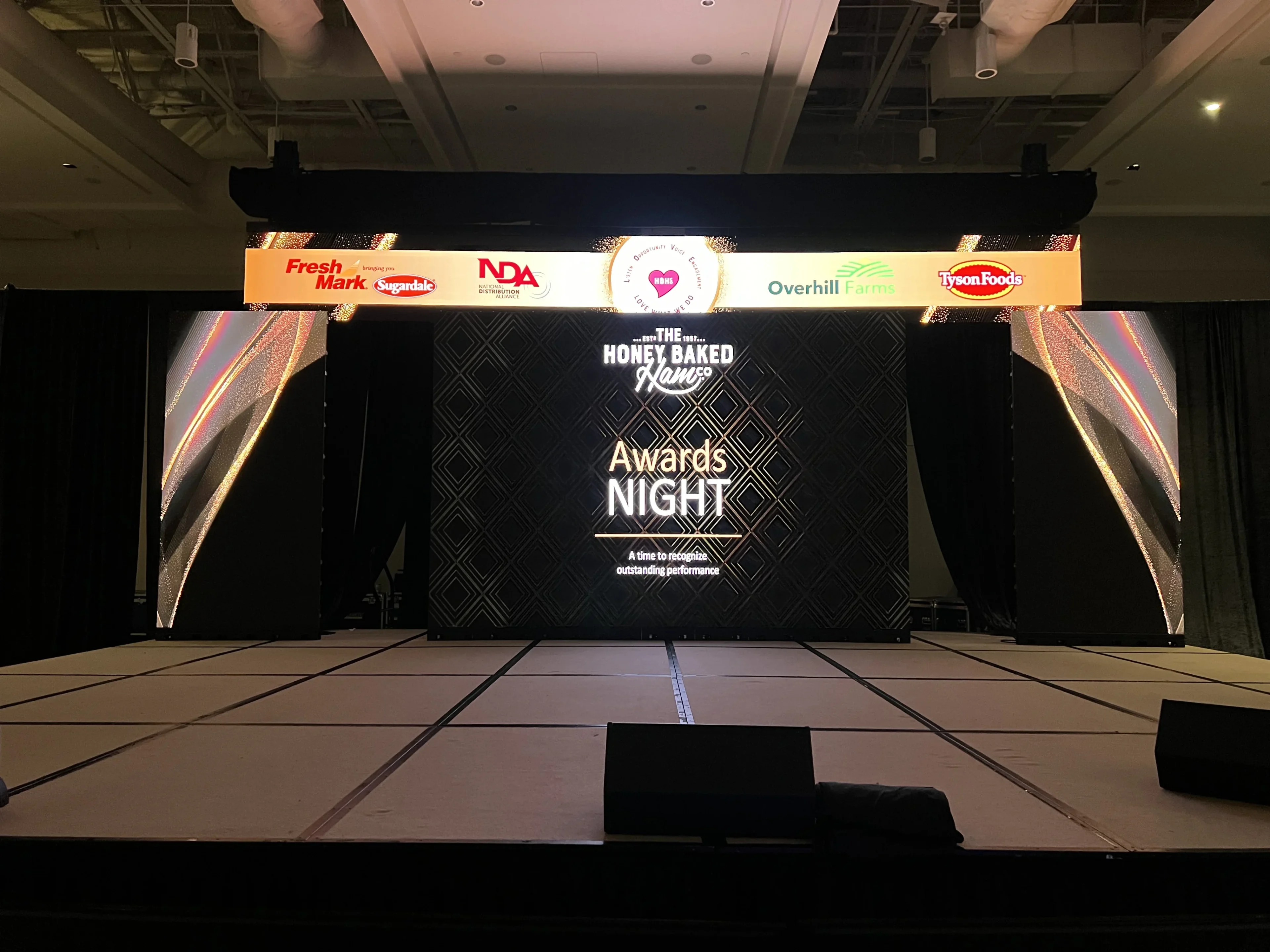 HoneyBaked Ham 'Awards Night' stage with wide LED backdrop and an overhead sponsor banner featuring Fresh Mark, Sugardale, NDA, Overhill Farms and Tyson Foods