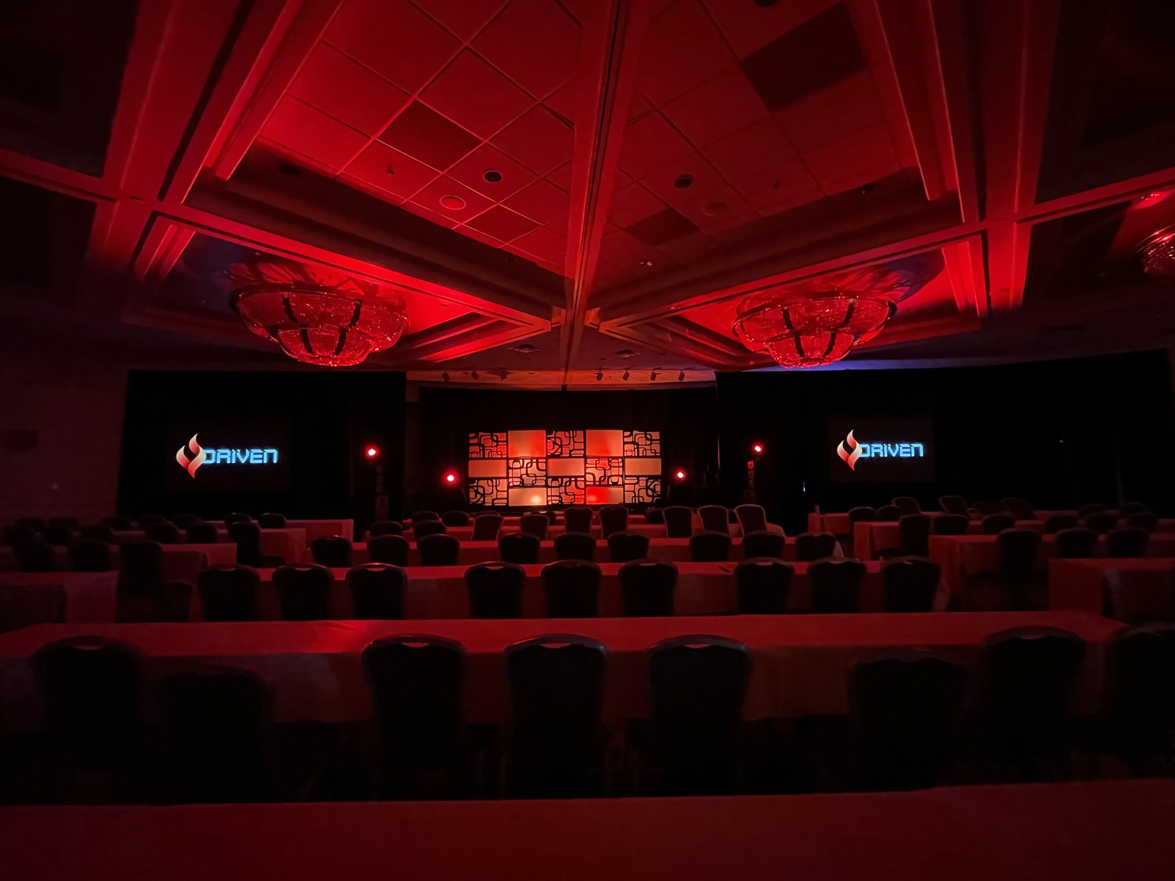 Conference keynote with dramatic deep red uplighting washing ballroom walls and ceiling