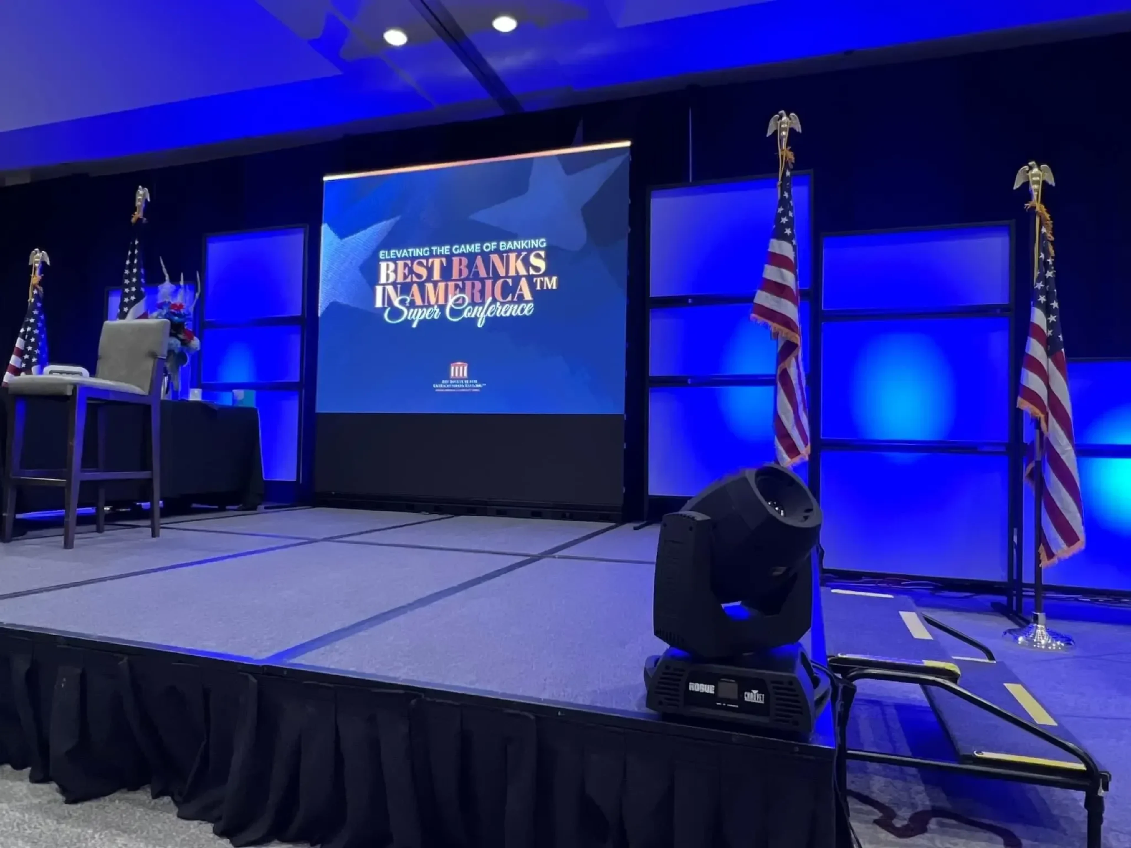 Best Banks in America Super Conference set with dual side LED screens reading 'Elevating the Game of Banking', US flags and a moving-head pre-show check