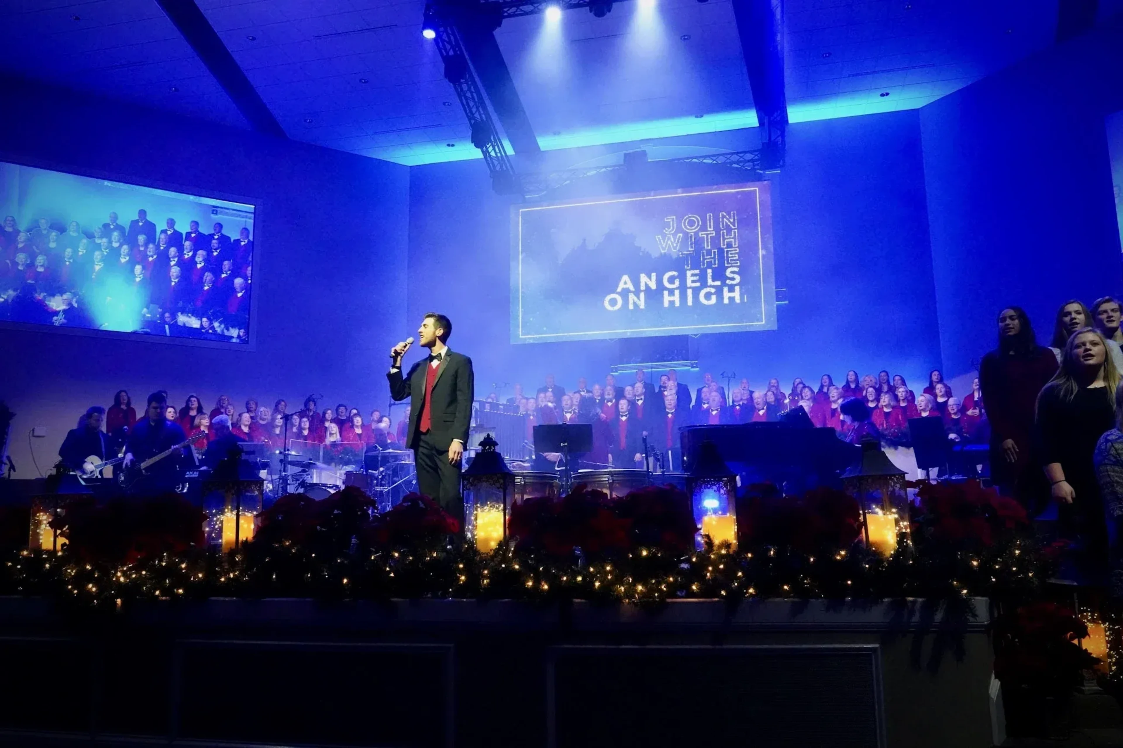 Church Christmas production with performer on stage, choir, and LED video walls displaying worship graphics in blue lighting