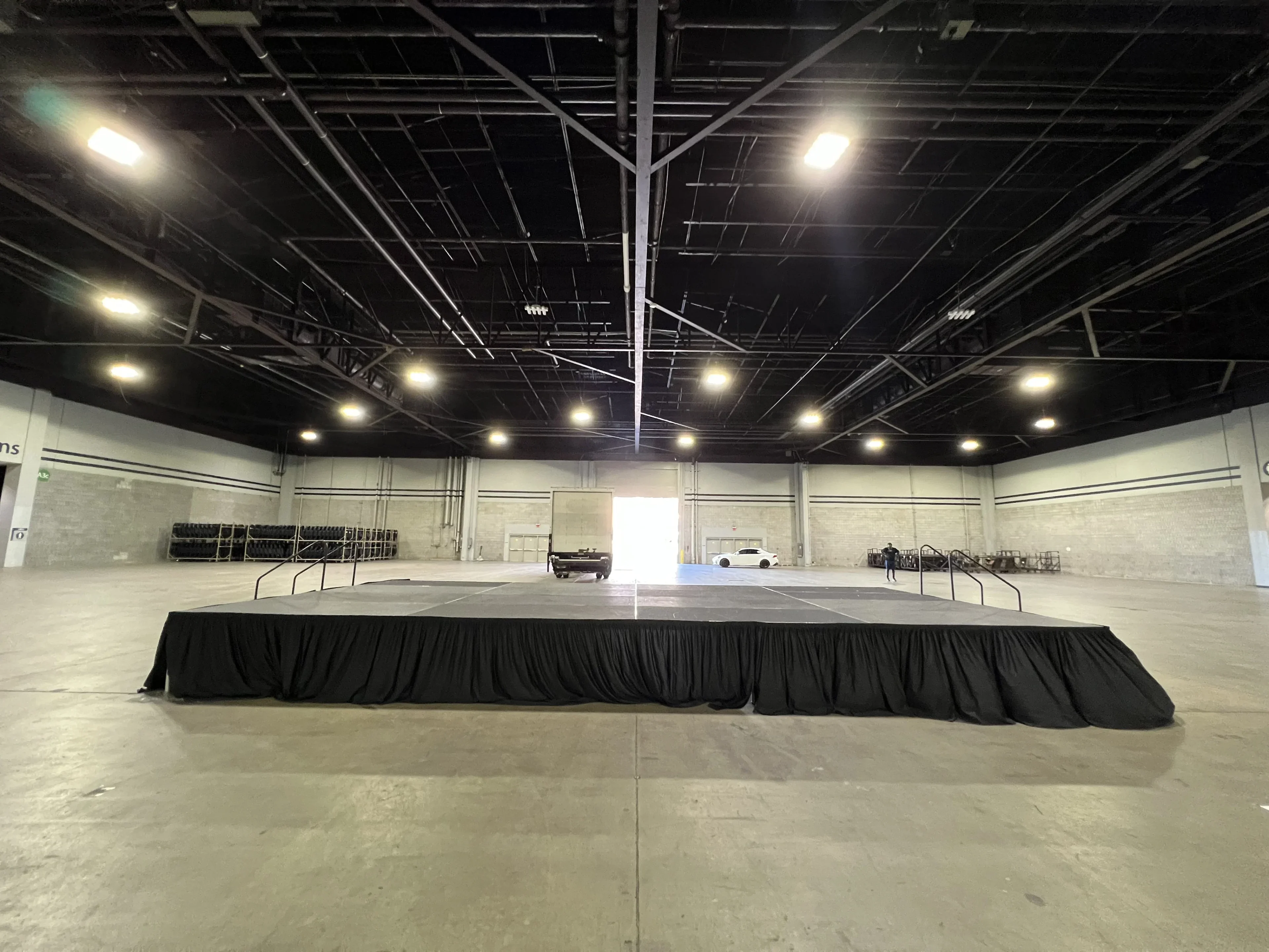 Large black-skirted modular deck stage set up in a convention center exhibit hall