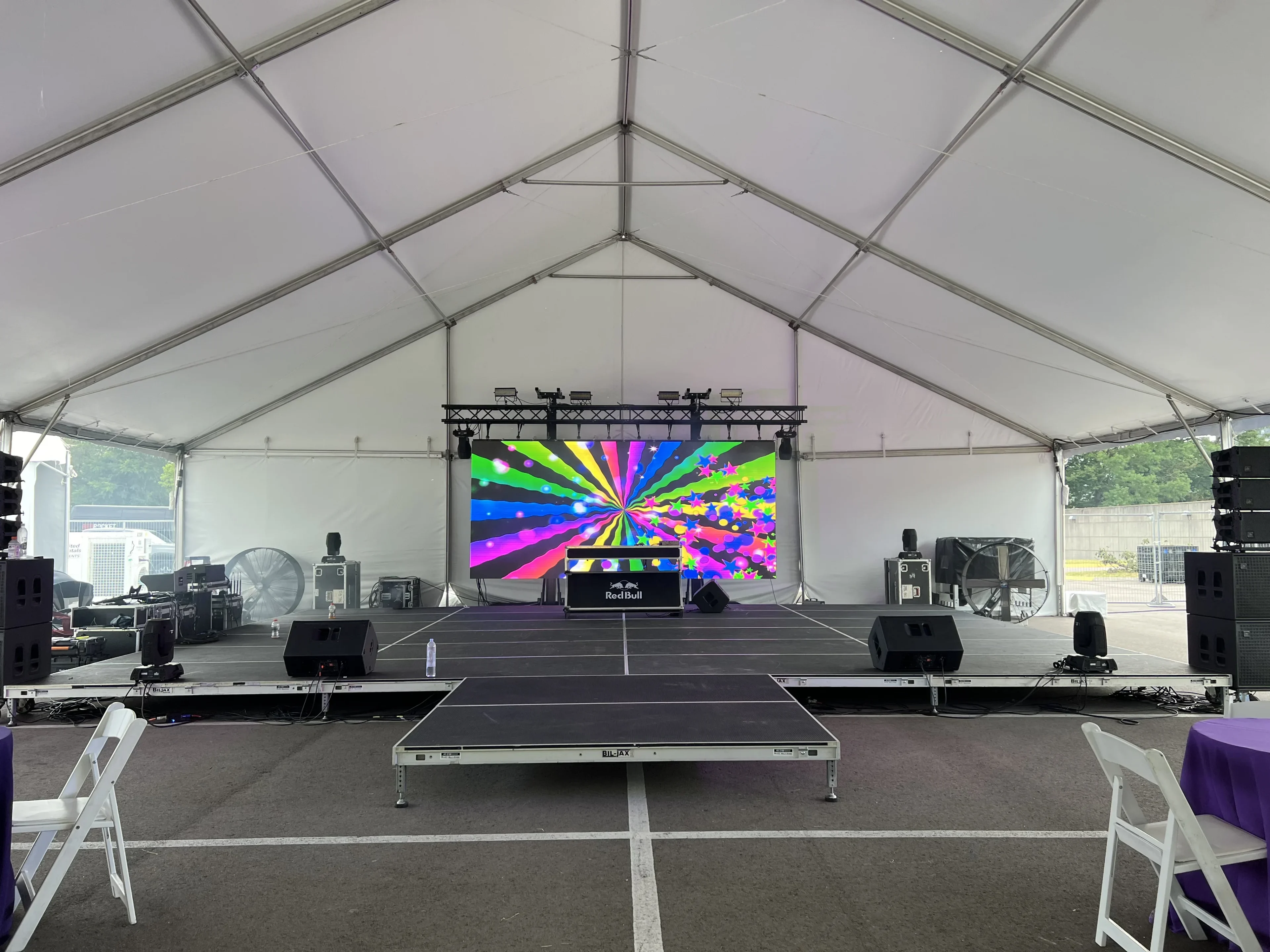 Tiered deck staging with LED video wall and line array speakers under large event tent