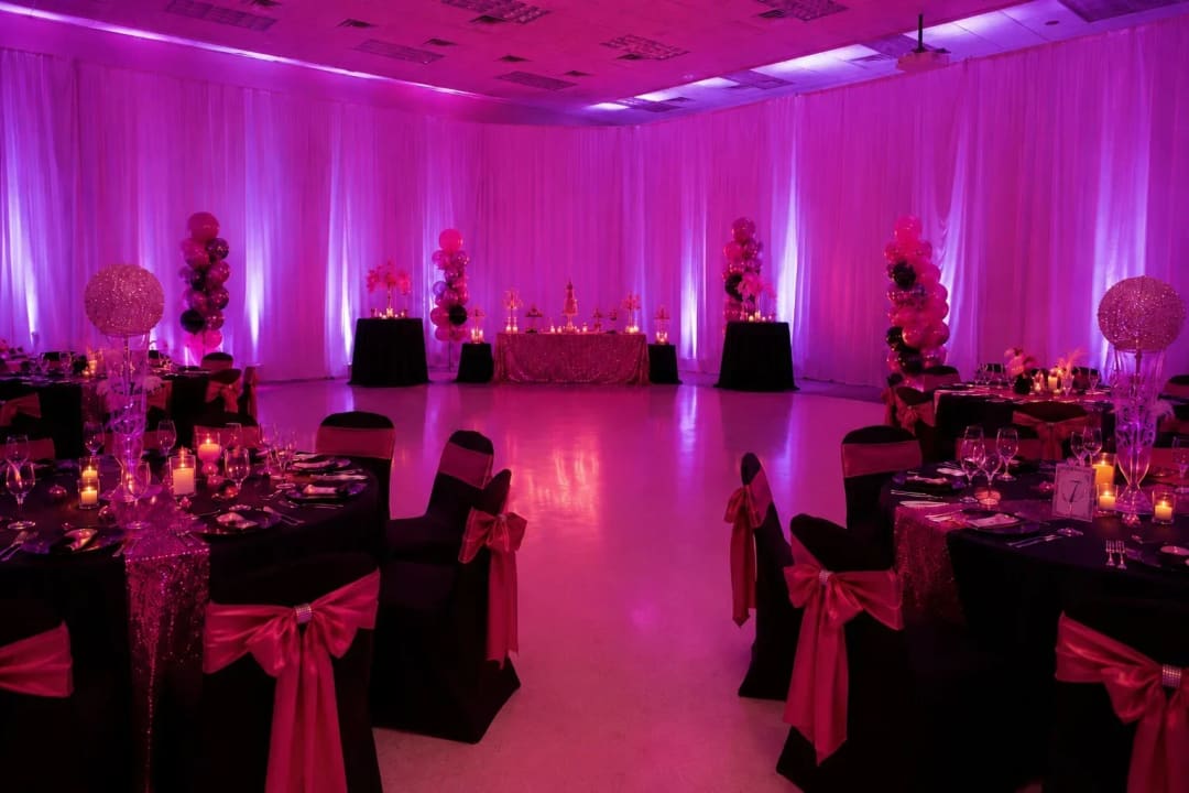 Pink and magenta uplighting washing white drape walls at an Atlanta reception.