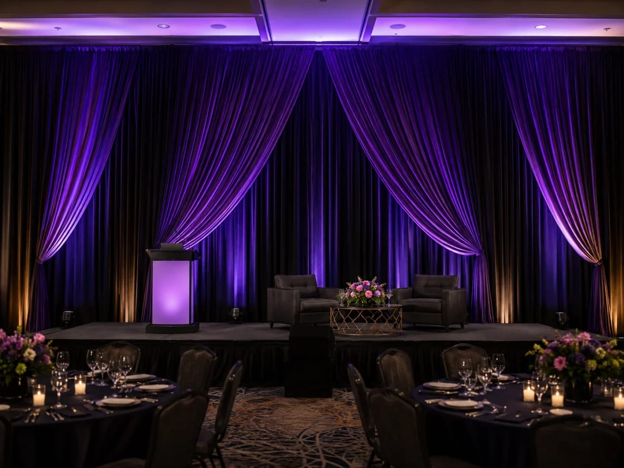 Uplit draped backdrop wall behind a lounge and stage at an Atlanta event.