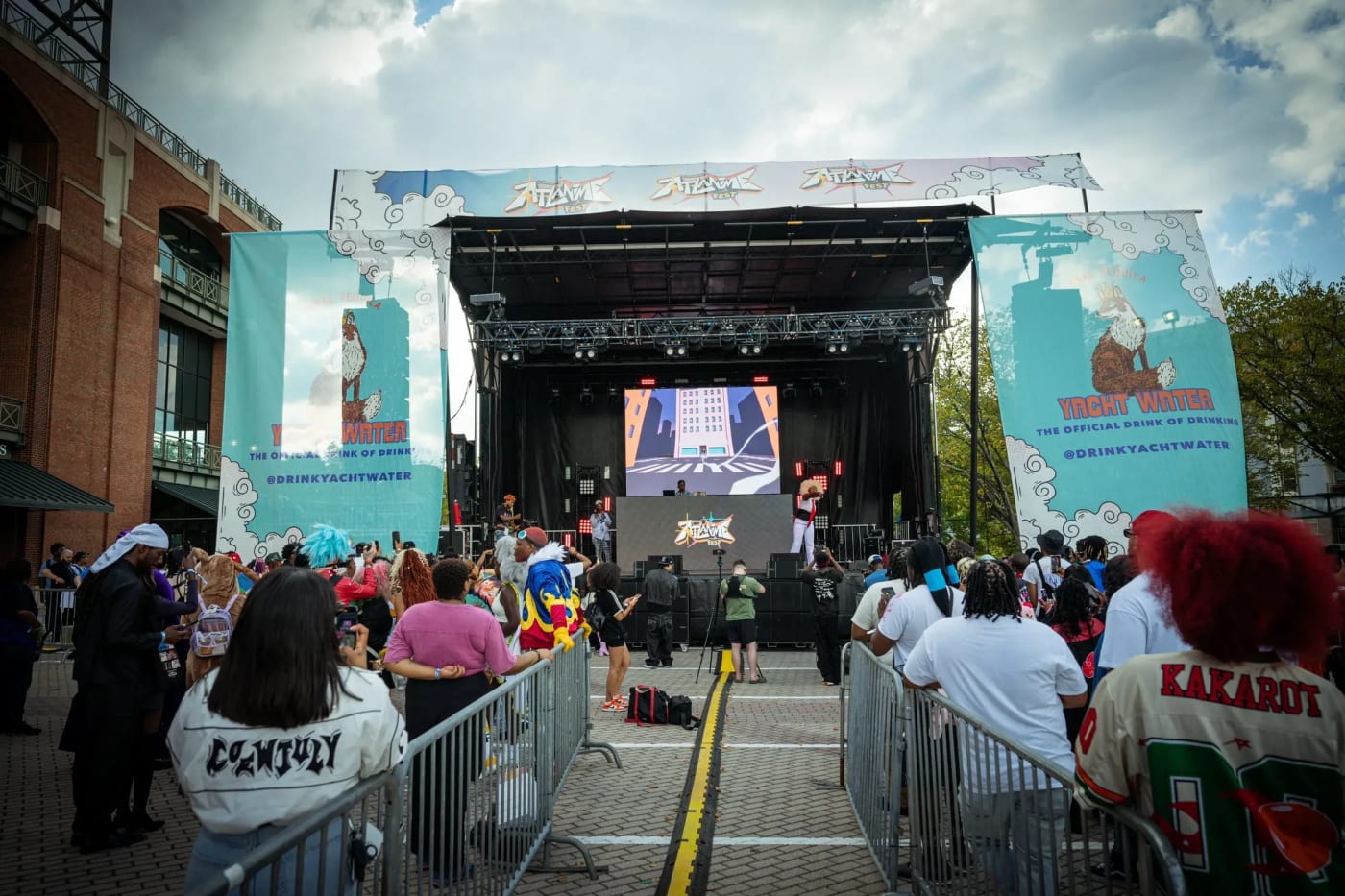 ATL Anime Fest outdoor stage with LED screen, truss rig, and cosplay crowd