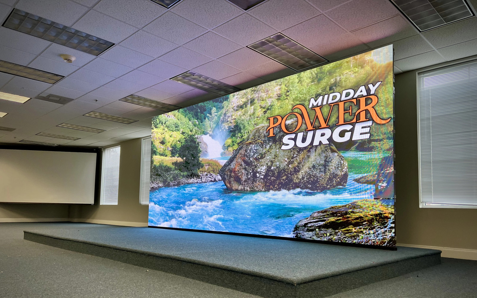 Ground-supported LED wall on raised stage in conference room displaying branded content