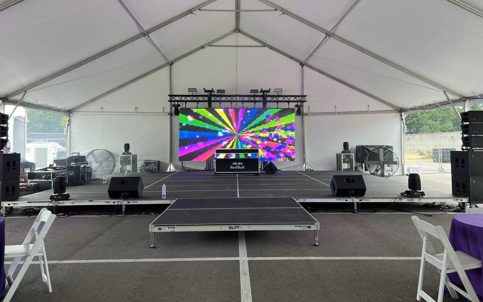 Tiered deck staging with LED video wall and line array speakers under large event tent