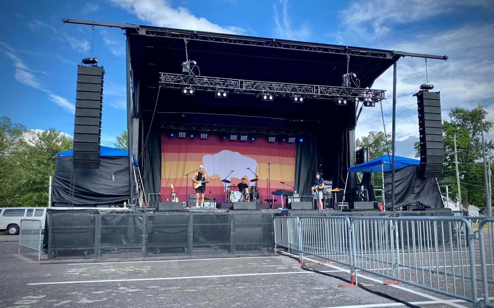 Live band performing on outdoor truss stage with LED backdrop and dual line arrays during a campus spring festival