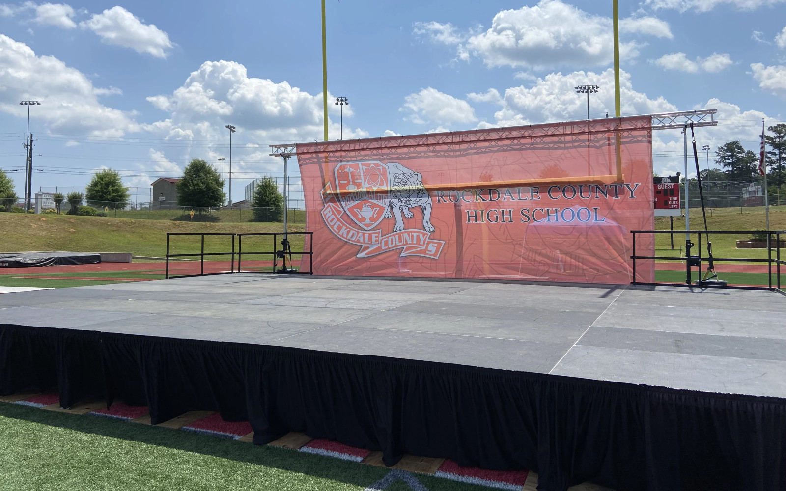 Rockdale County High School outdoor graduation stage on football field with large custom branded backdrop banner
